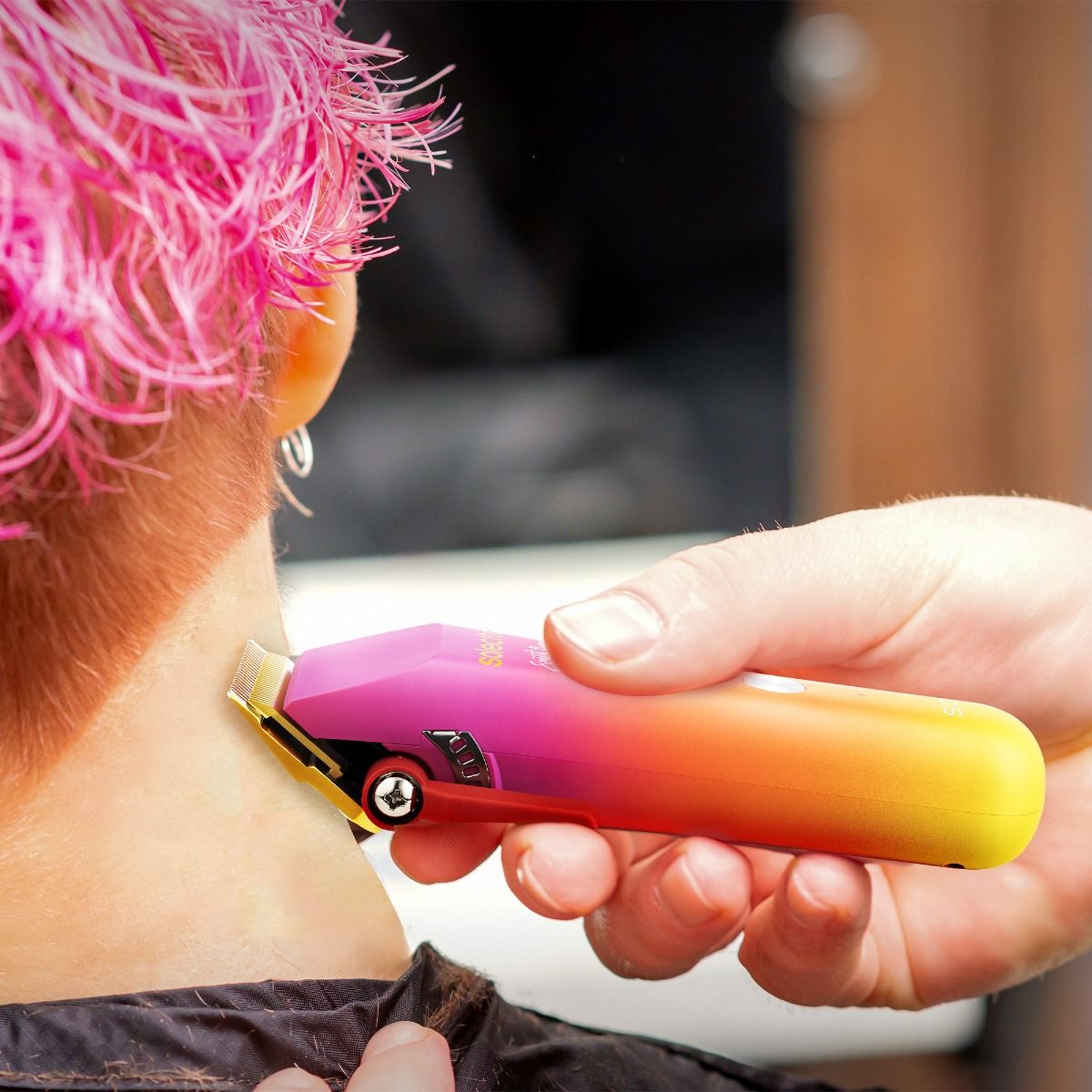 Handheld professional hair clipper with rainbow orange-to-purple body and charging base grip